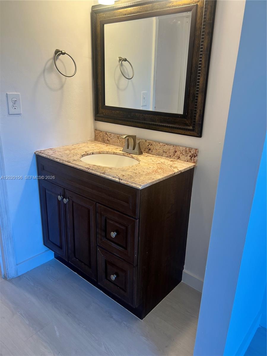 A bathroom vanity features a dark wood cabinet, granite countertop, and a framed wall mirror — 3621 NW 95th Ter # 523, Sunrise FL 33351, SUNRISE, FL