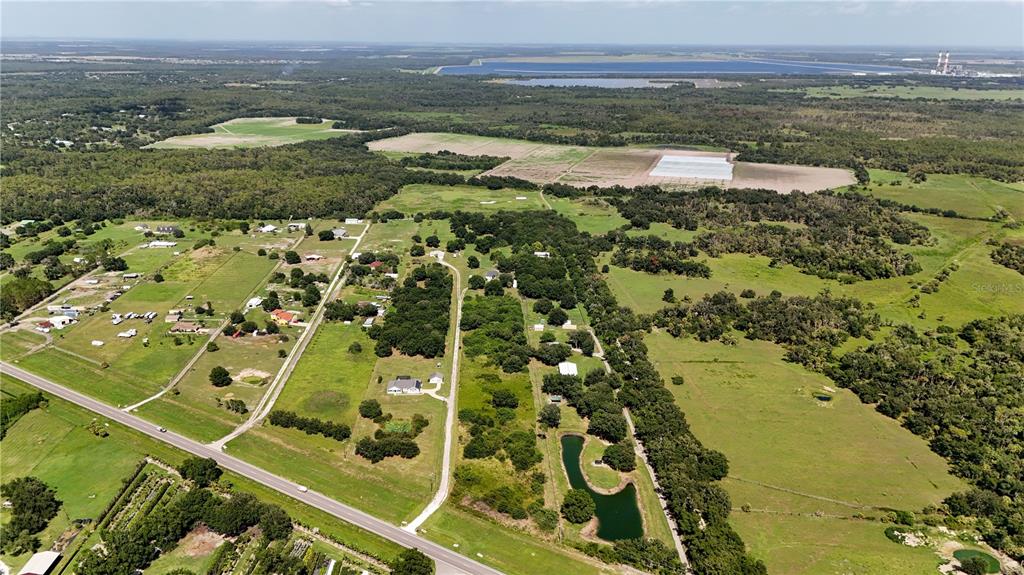 An aerial view shows a rural landscape with scattered houses, pastures, trees, and a pond — 14775 US HIGHWAY 301 N, PARRISH, FL