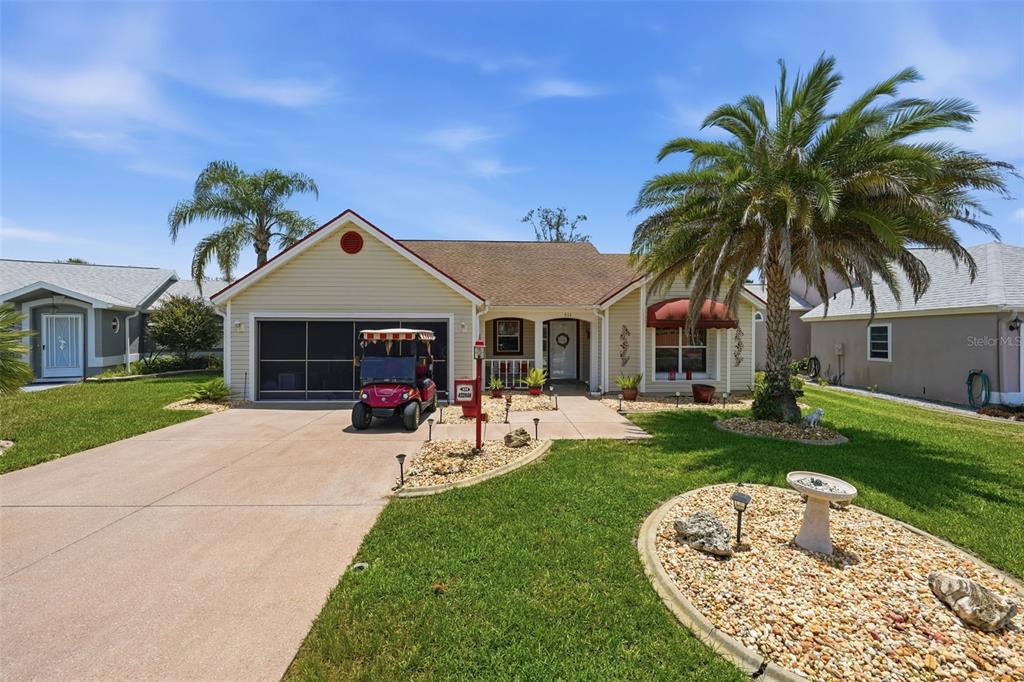 A covered front porch features a white metal bench, light siding, and a concrete floor — 511 SAN LORENZO COURT, THE VILLAGES, FL