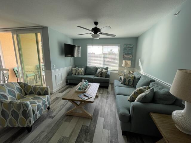A living room features light blue walls, wood-look flooring, a ceiling fan, and blue sofas — 110 Villa Circle # 110, Boynton Beach FL 33435, BOYNTON BEACH, FL