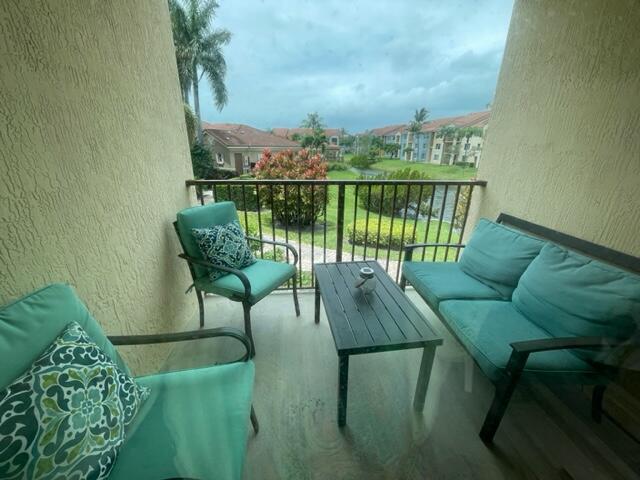 A balcony features a small table, a loveseat, and a chair with teal cushions — 110 Villa Circle # 110, Boynton Beach FL 33435, BOYNTON BEACH, FL