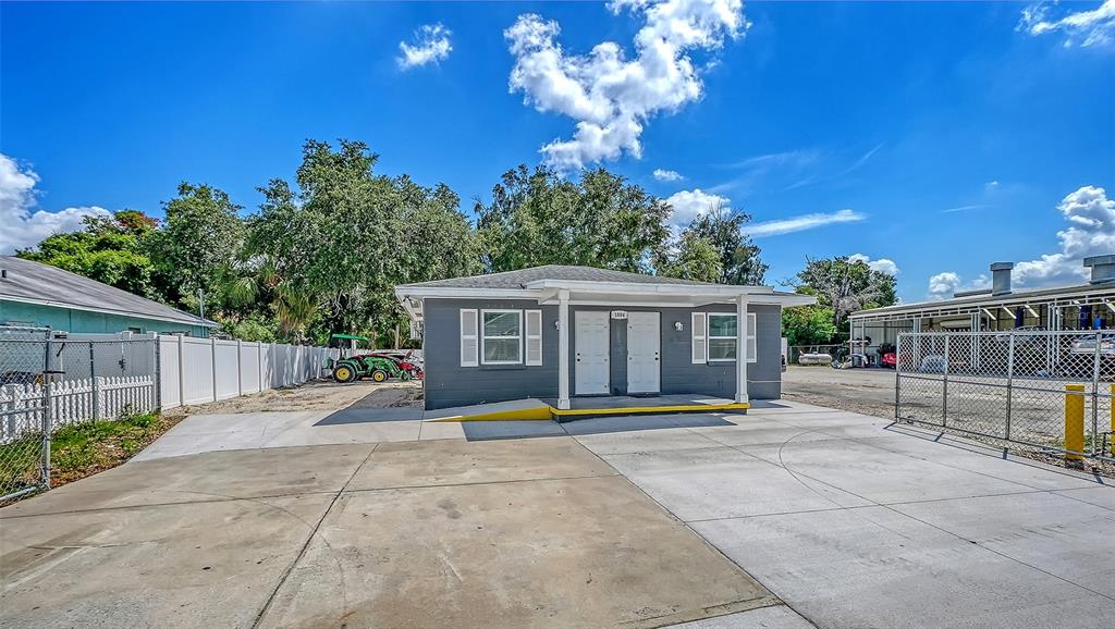 A gray single-story building with a concrete driveway and a white fence — 1004 27TH AVENUE W, BRADENTON, FL