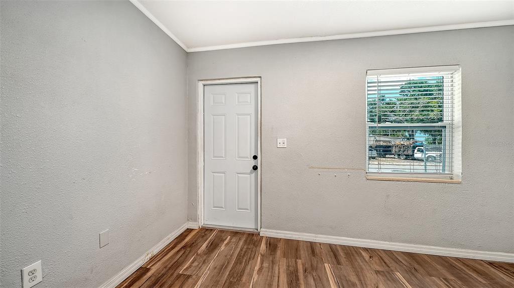 A room with grey walls, wood-look flooring, a white door, and a window with blinds — 1004 27TH AVENUE W, BRADENTON, FL