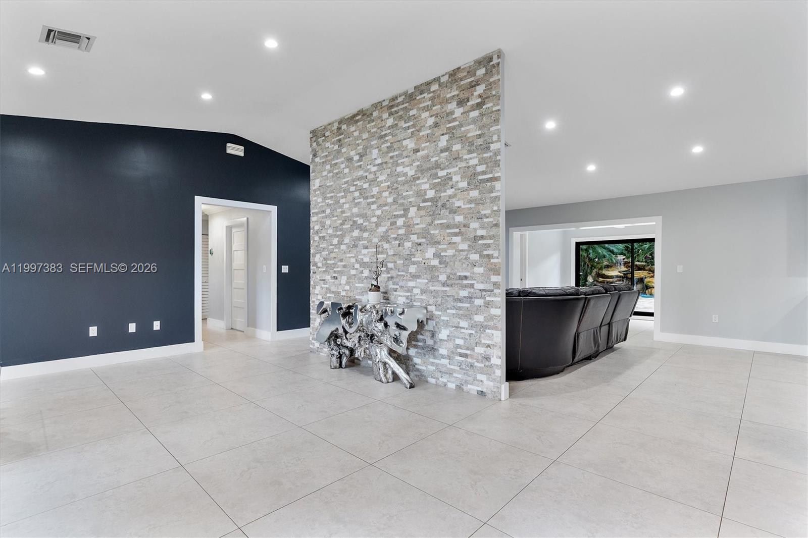 A living room features a stone accent wall, dark blue paint, and light tile flooring — 14800 SW 166th St, Miami FL 33187, MIAMI, FL