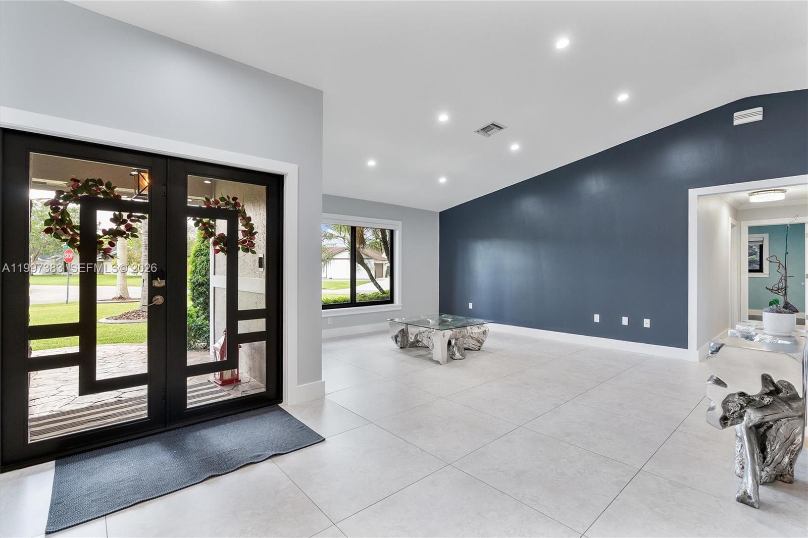 This bright entryway features large light-colored floor tiles, a dark accent wall, and glass doors — 14800 SW 166th St, Miami FL 33187, MIAMI, FL