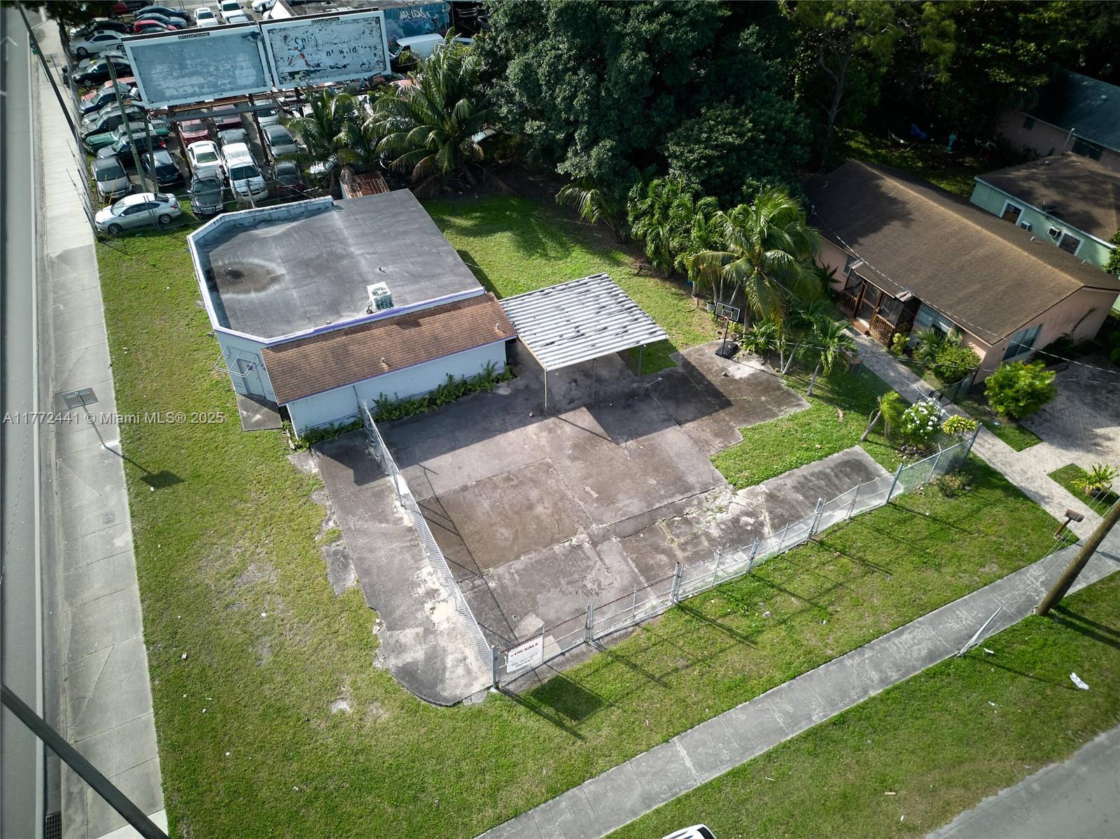 An aerial view shows a commercial building with a fenced concrete lot and carport — 5832 NW 27th Ave, Miami FL 33142, MIAMI, FL