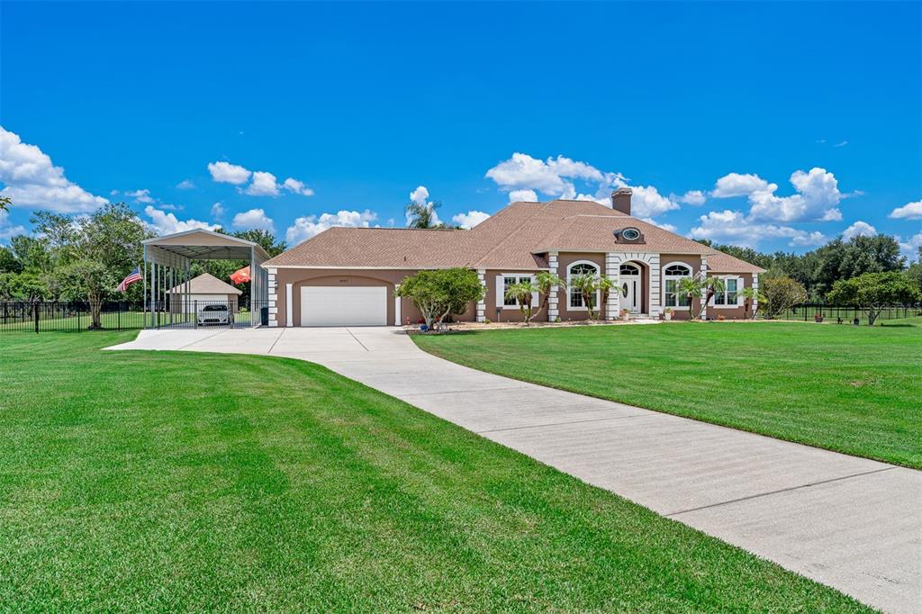 A single-story house with a brown roof, tan stucco exterior, and a large concrete driveway — 8627 BOW COURT, ORLANDO, FL