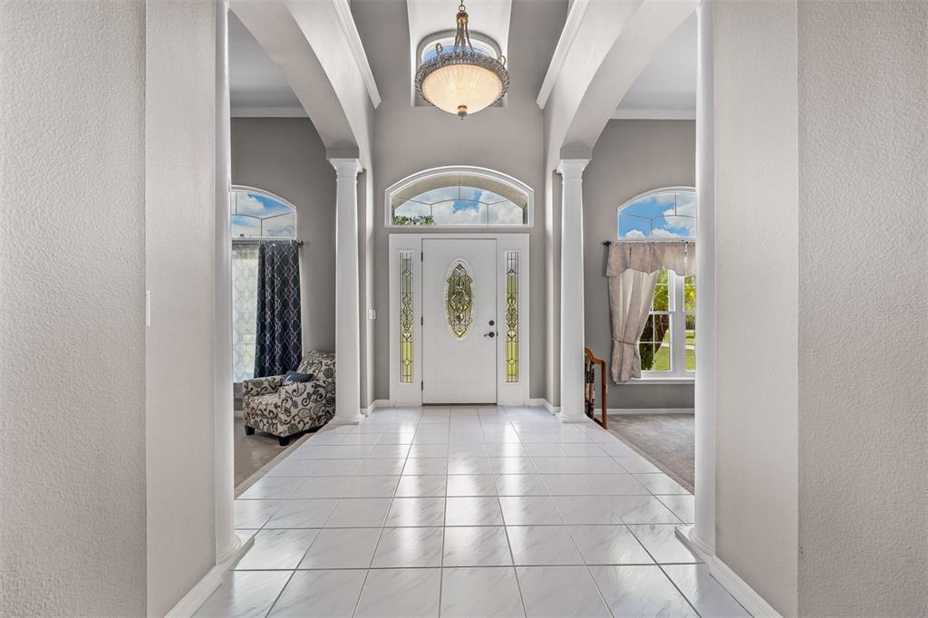 A bright foyer features white tiled floors, tall columns, and a central arched entryway — 8627 BOW COURT, ORLANDO, FL