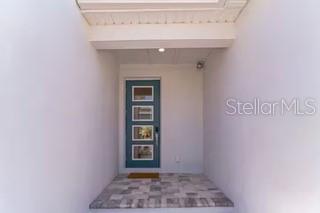 A teal front door with four glass panels sits under a covered entryway — 7842 SPECTRUM DRIVE, REUNION, FL