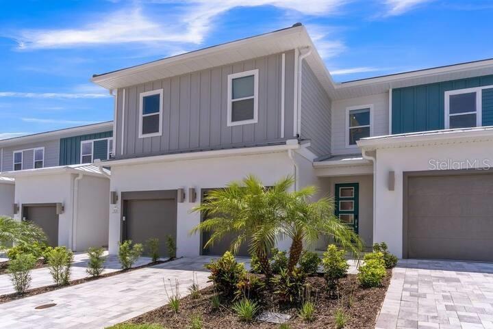 A row of modern two-story townhomes features white stucco, gray vertical siding, and paved driveways — 7842 SPECTRUM DRIVE, REUNION, FL