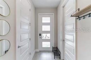 A bright entryway features white paneled doors, three circular wall mirrors, and a wooden wall shelf — 7842 SPECTRUM DRIVE, REUNION, FL