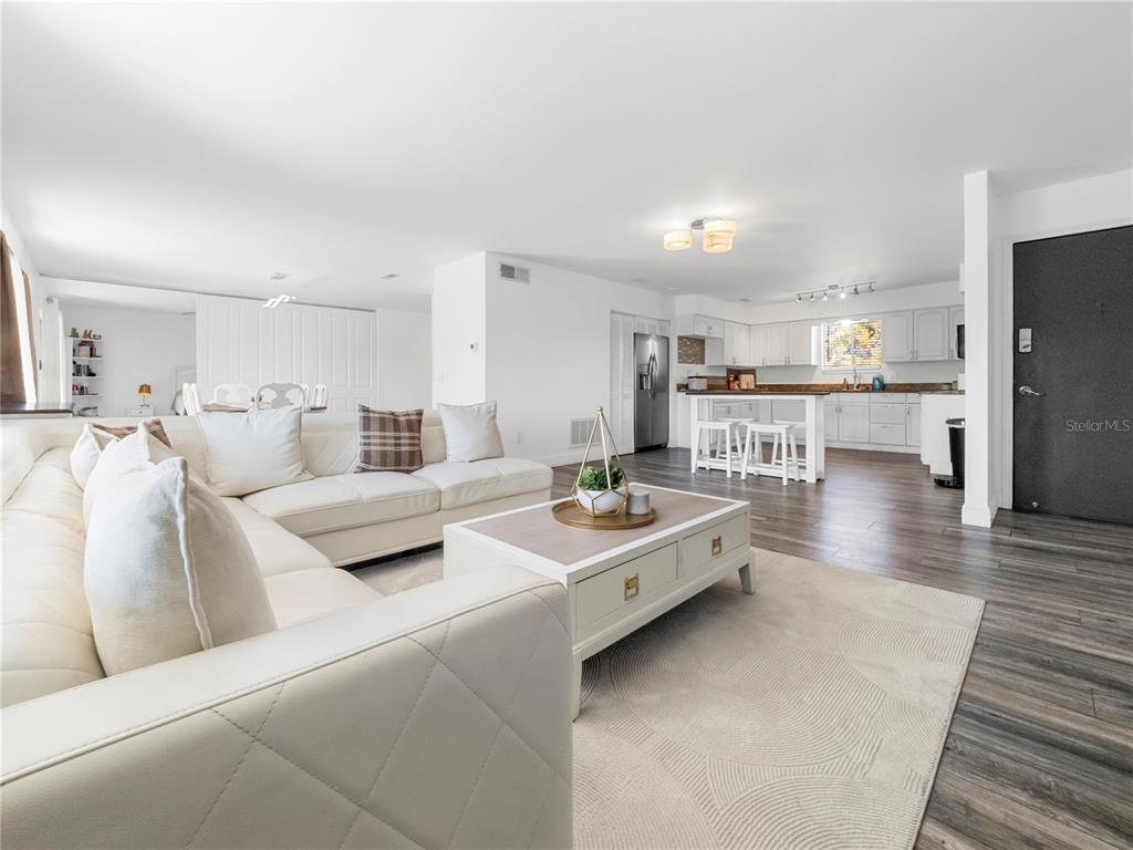 A bright open-concept living room features a white sectional sofa, coffee table, and kitchen area — 4036 CORTEZ DRIVE UNIT D, TAMPA, FL