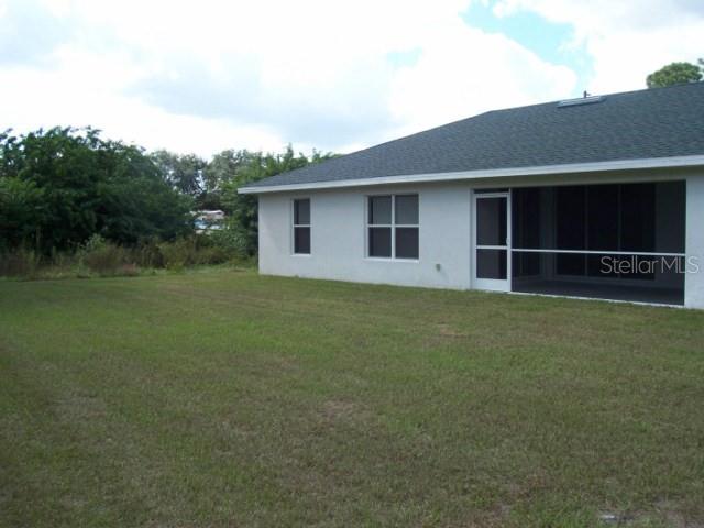 The exterior of a house features a screened-in porch and a large grassy backyard — 1491 GLENVIEW ROAD, NORTH PORT, FL