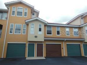 A multi-story tan townhouse exterior features several garage doors and a central entrance door — 12414 BALERIA COVE UNIT 105, ORLANDO, FL