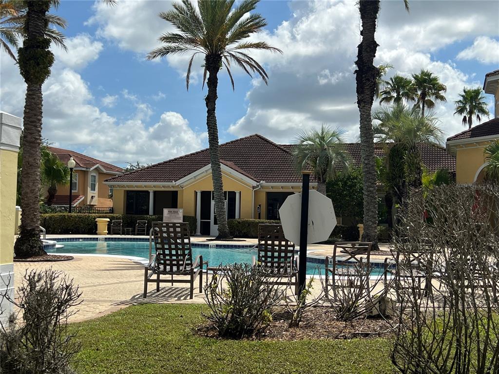 A swimming pool sits in front of a yellow building surrounded by palm trees — 12414 BALERIA COVE UNIT 105, ORLANDO, FL