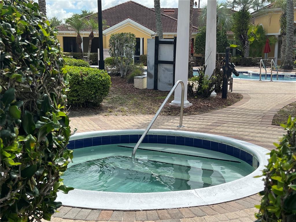 A round outdoor hot tub with a metal handrail sits on a paved pool deck — 12414 BALERIA COVE UNIT 105, ORLANDO, FL