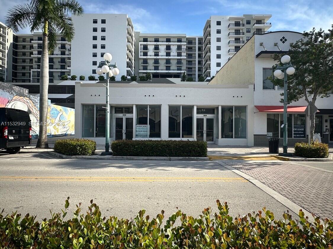 A single-story commercial building with large glass windows sits in front of a tall apartment complex — 2020 Harrison St, Hollywood FL 33020, HOLLYWOOD, FL