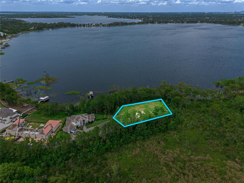 An aerial view shows a vacant, wooded waterfront lot outlined in blue next to a house — MANTOVA COURT, ORLANDO, FL
