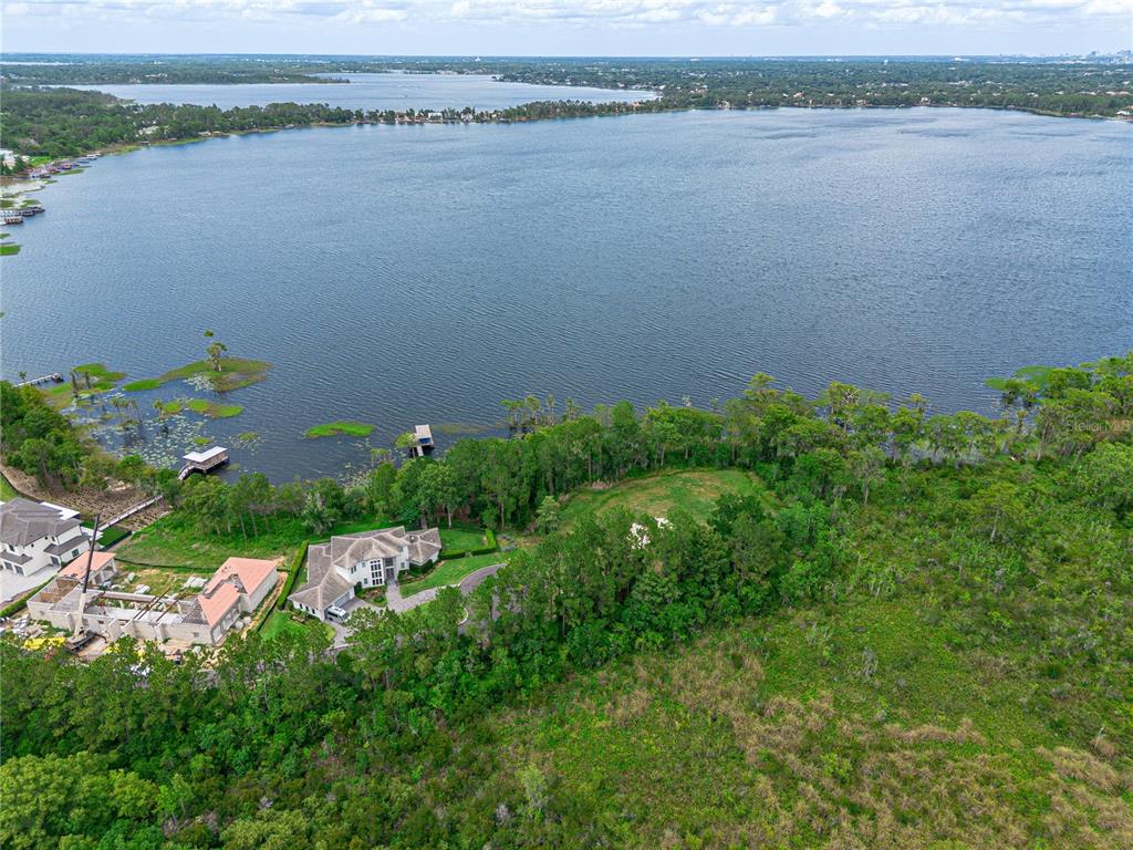 An aerial view shows a large house with a pool situated beside a lake — MANTOVA COURT, ORLANDO, FL