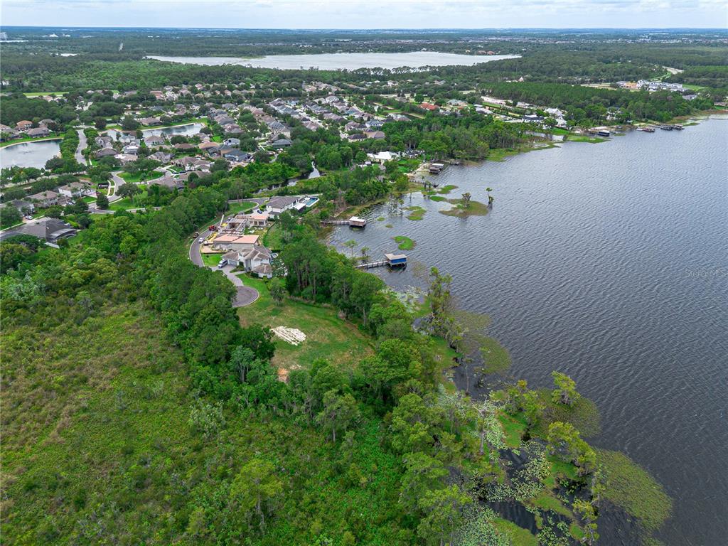 An aerial view shows a waterfront home surrounded by trees and a large lake — MANTOVA COURT, ORLANDO, FL