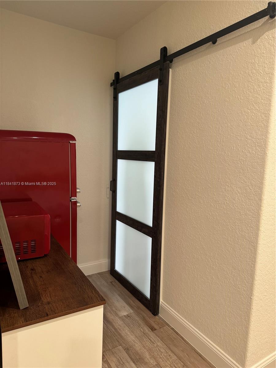 A sliding barn door with frosted glass panels is installed next to a red refrigerator — 15603 SW 178th St, Miami FL 33187, MIAMI, FL
