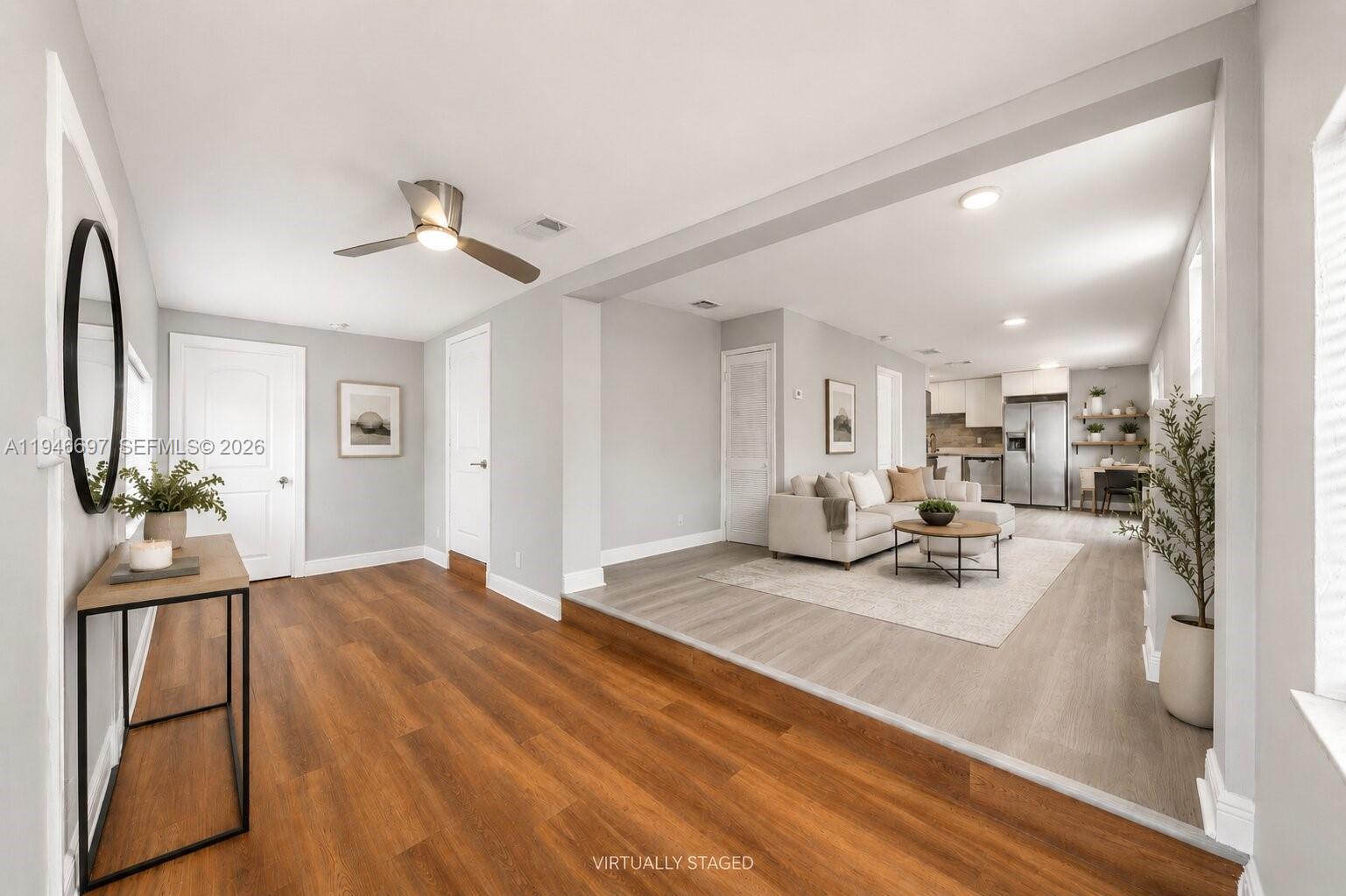 A living room and kitchen area with light gray walls and wood-look flooring — 1726 Roosevelt St, Hollywood FL 33020, HOLLYWOOD, FL