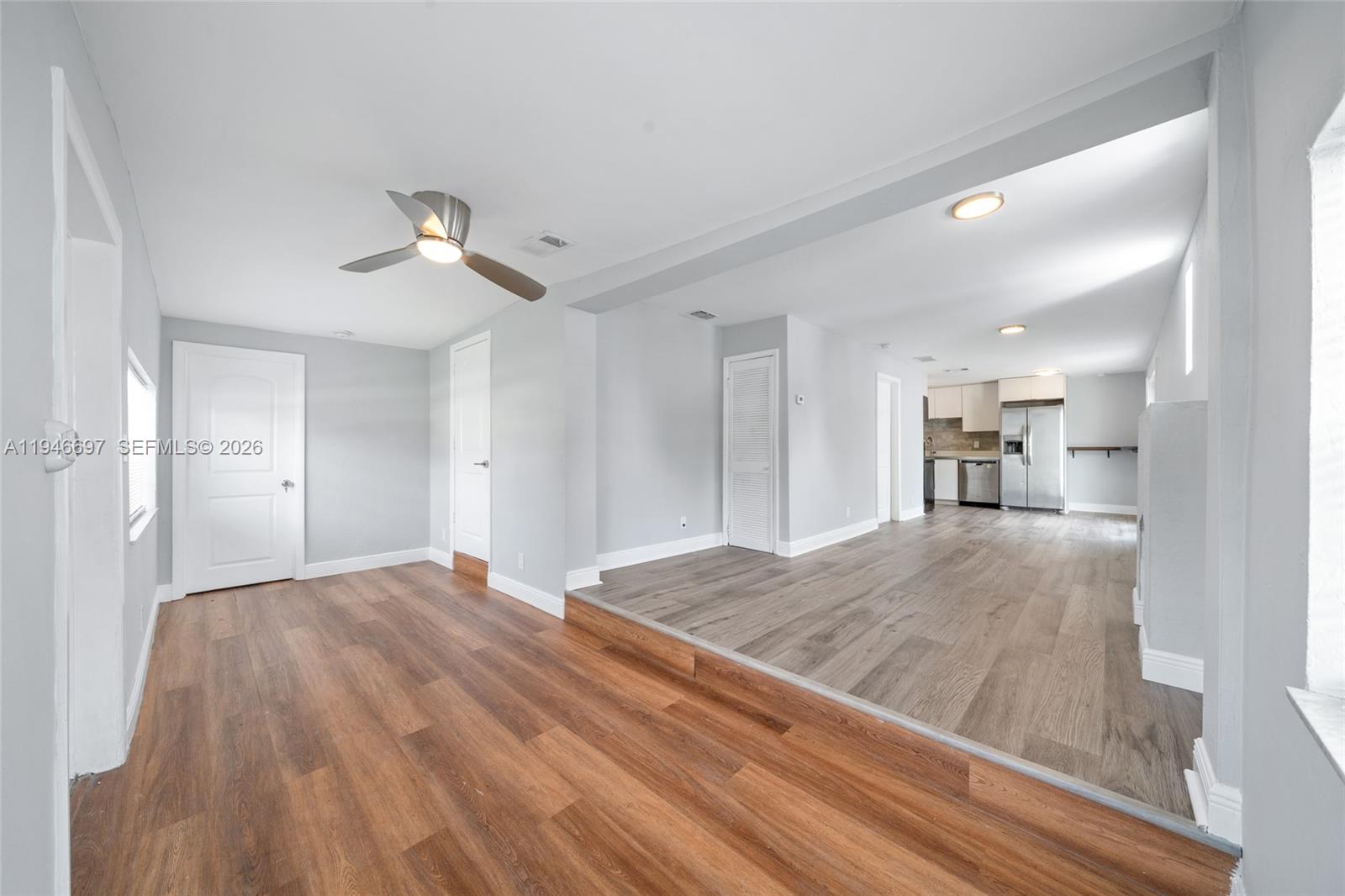 A living area with a sunken kitchen features light gray walls and wood-look flooring — 1726 Roosevelt St, Hollywood FL 33020, HOLLYWOOD, FL