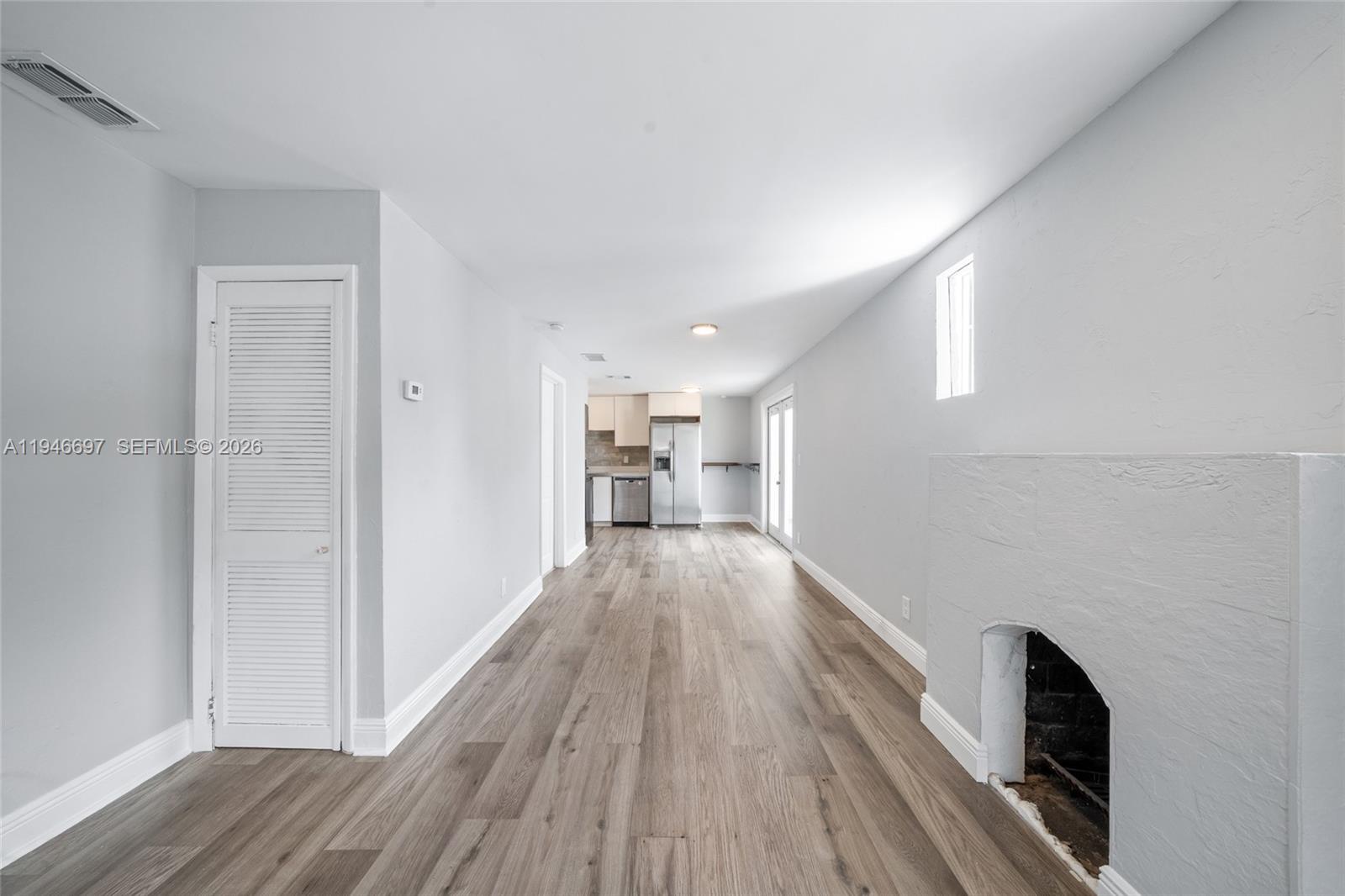 This living room features light gray walls, wood-look flooring, and a white brick fireplace — 1726 Roosevelt St, Hollywood FL 33020, HOLLYWOOD, FL
