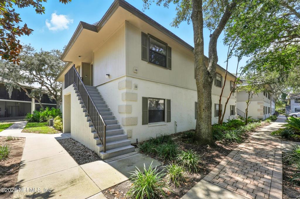An exterior view of a two-story apartment building with an outdoor staircase and brick walkways — 14 NAVARRA COURT UNIT 14, ST AUGUSTINE, FL