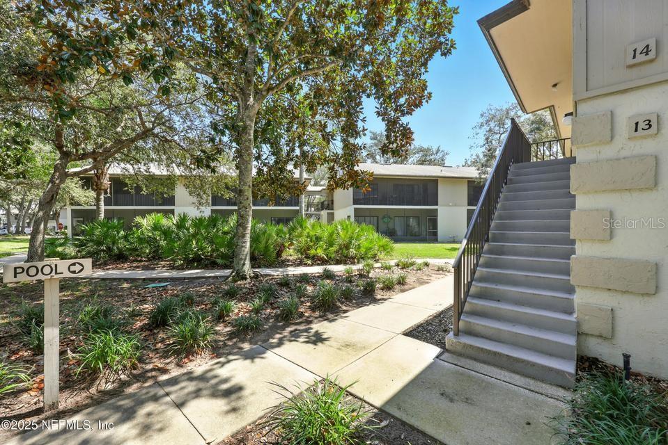 An exterior view shows a concrete staircase leading to upper-level apartment units near a pool — 14 NAVARRA COURT UNIT 14, ST AUGUSTINE, FL