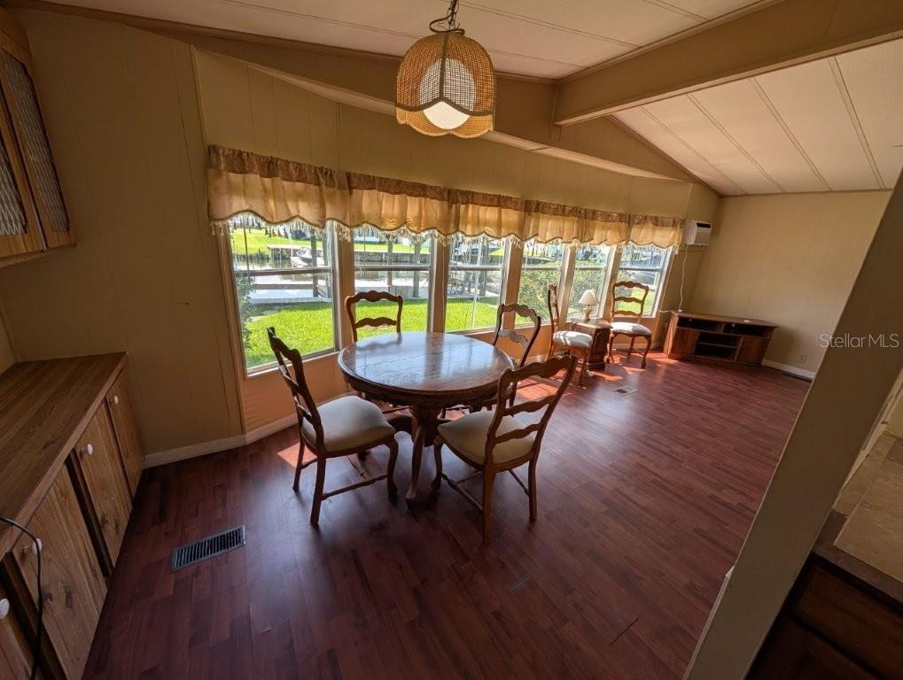 A dining area with a round wooden table, four chairs, and large windows overlooking grass — 154 MOONLITE DRIVE, WELAKA, FL