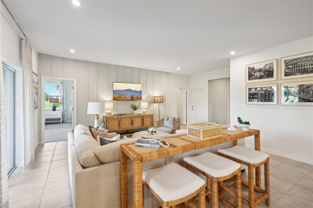 A living room features a sofa, a console table with stools, and a wall-mounted television — 12906 CARA COURT, GRAND ISLAND, FL