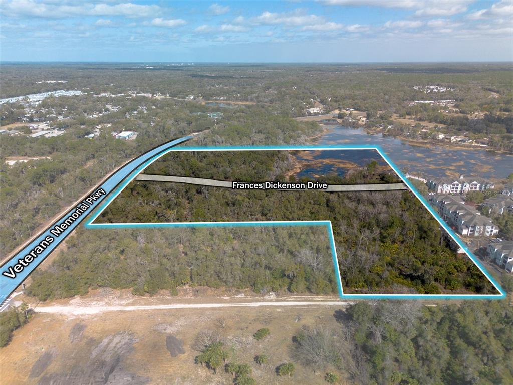 An aerial view shows a large, undeveloped plot of land outlined in blue — VETERANS MEMORIAL PARKWAY, ORANGE CITY, FL
