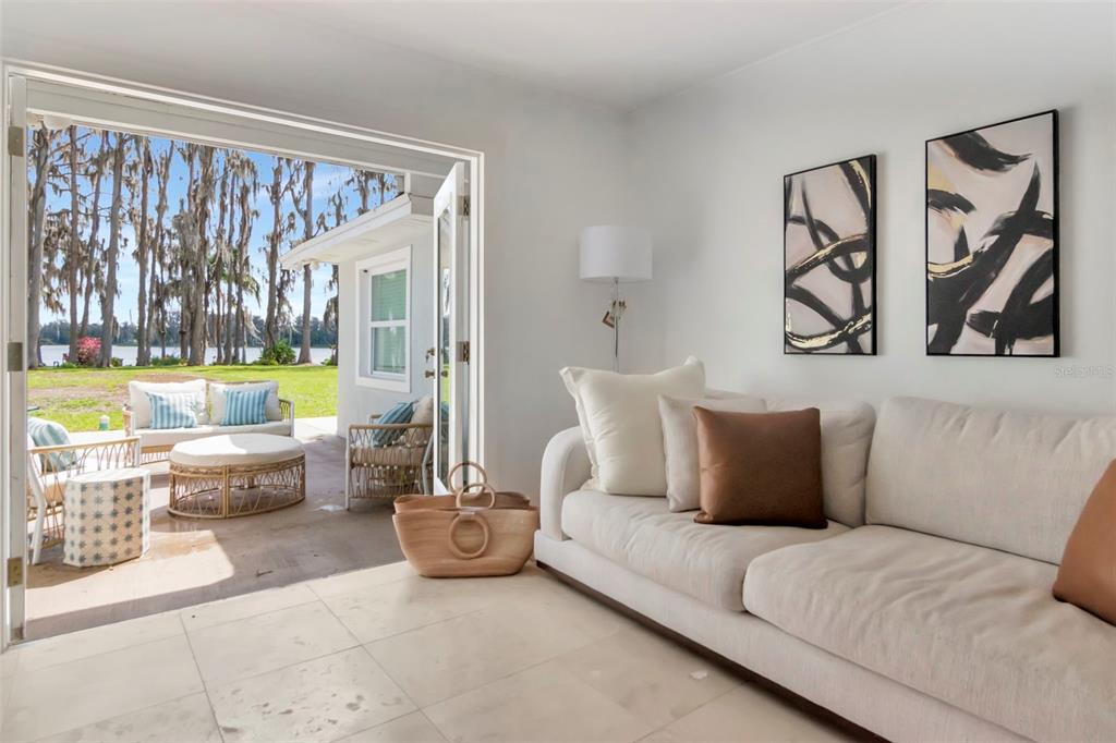 A living room with a white sofa opens onto a patio overlooking a lake — 19207 CROOKED LANE, LUTZ, FL