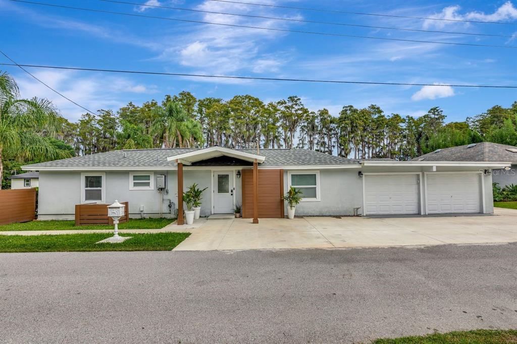 A single-story house with a white exterior, two garage doors, and a covered front entrance — 19207 CROOKED LANE, LUTZ, FL