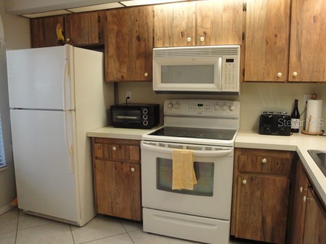 A kitchen with white appliances, wooden cabinets, and light-colored countertops — 6365 BAHIA DEL MAR BOULEVARD UNIT 113, ST PETERSBURG, FL
