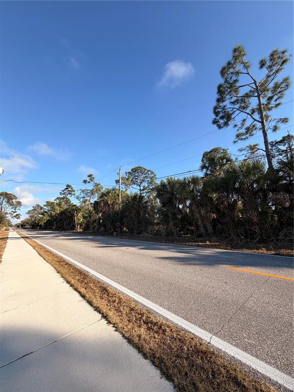 A paved road runs alongside a concrete sidewalk next to a wooded area — 9113 FRUITLAND AVENUE, ENGLEWOOD, FL