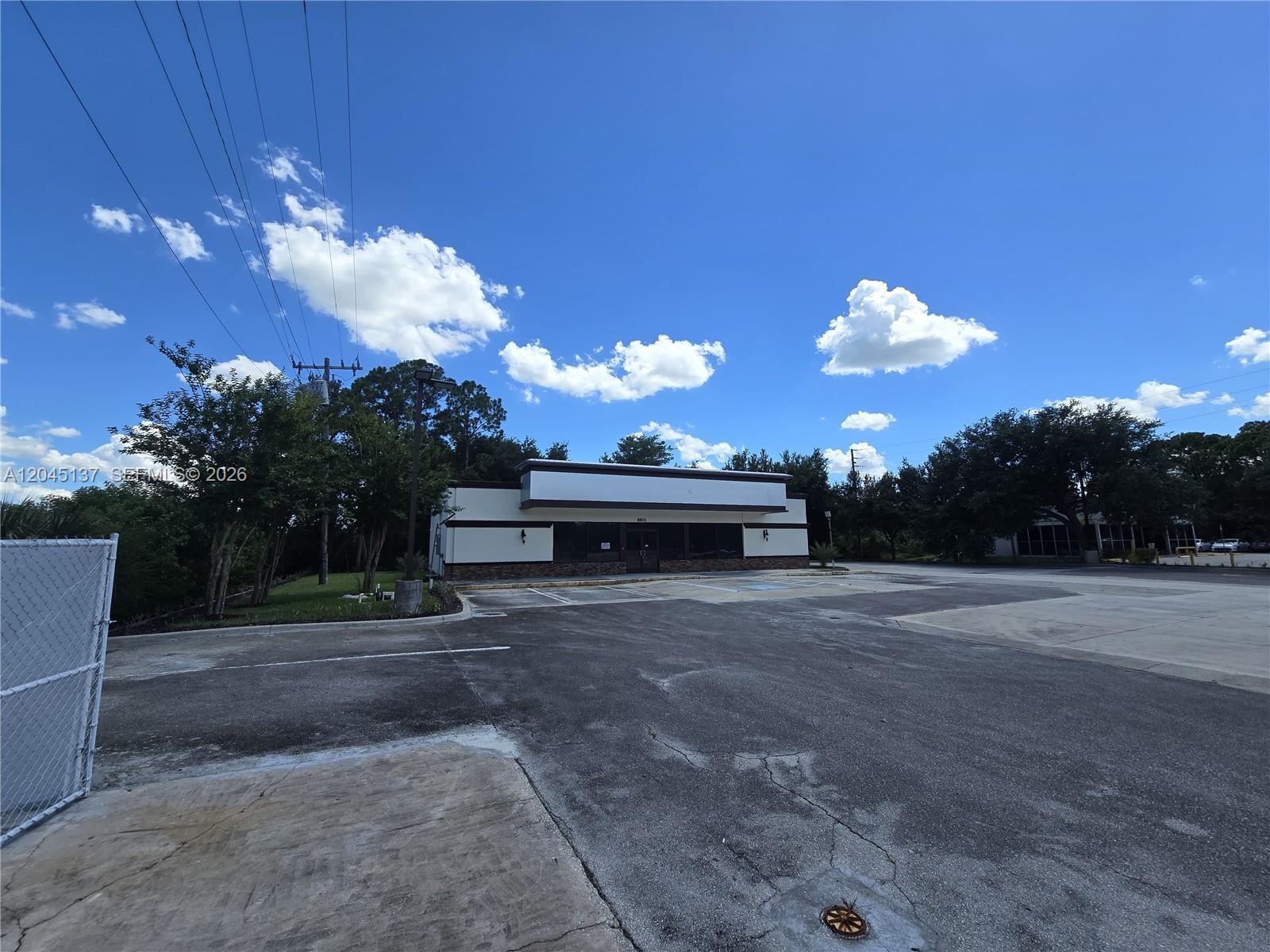 A standalone commercial building with a parking lot under a blue sky with clouds — 8801 20th St, Vero Beach FL 32966, VERO BEACH, FL