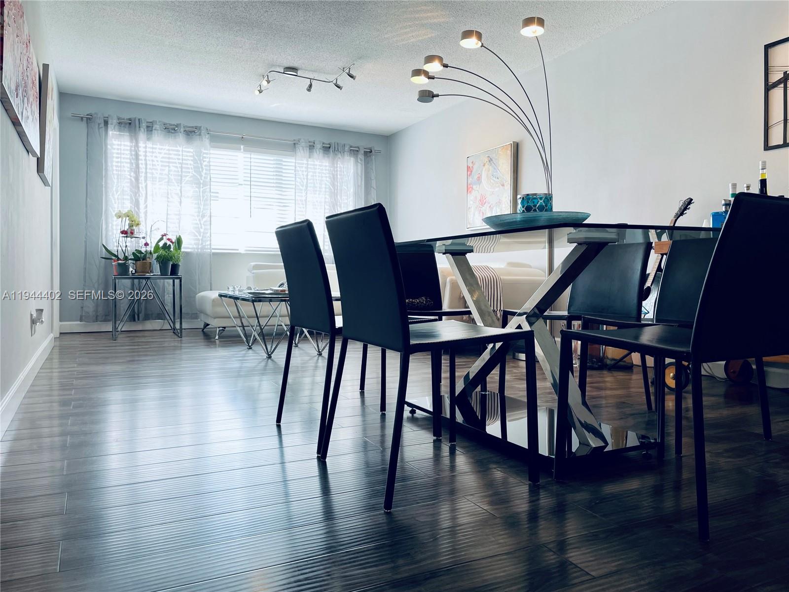A dining room features a glass table, black chairs, and dark wood-look flooring — 2300 Park Ln # 201, Hollywood FL 33021, HOLLYWOOD, FL