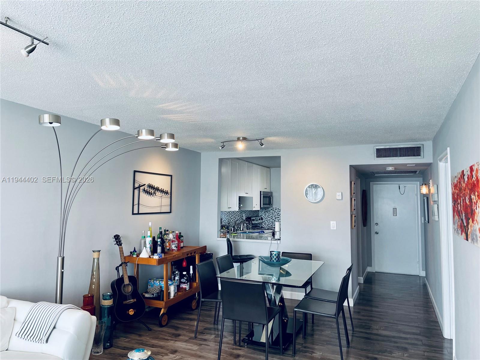 A dining area with a glass table, bar cart, and kitchen pass-through window — 2300 Park Ln # 201, Hollywood FL 33021, HOLLYWOOD, FL