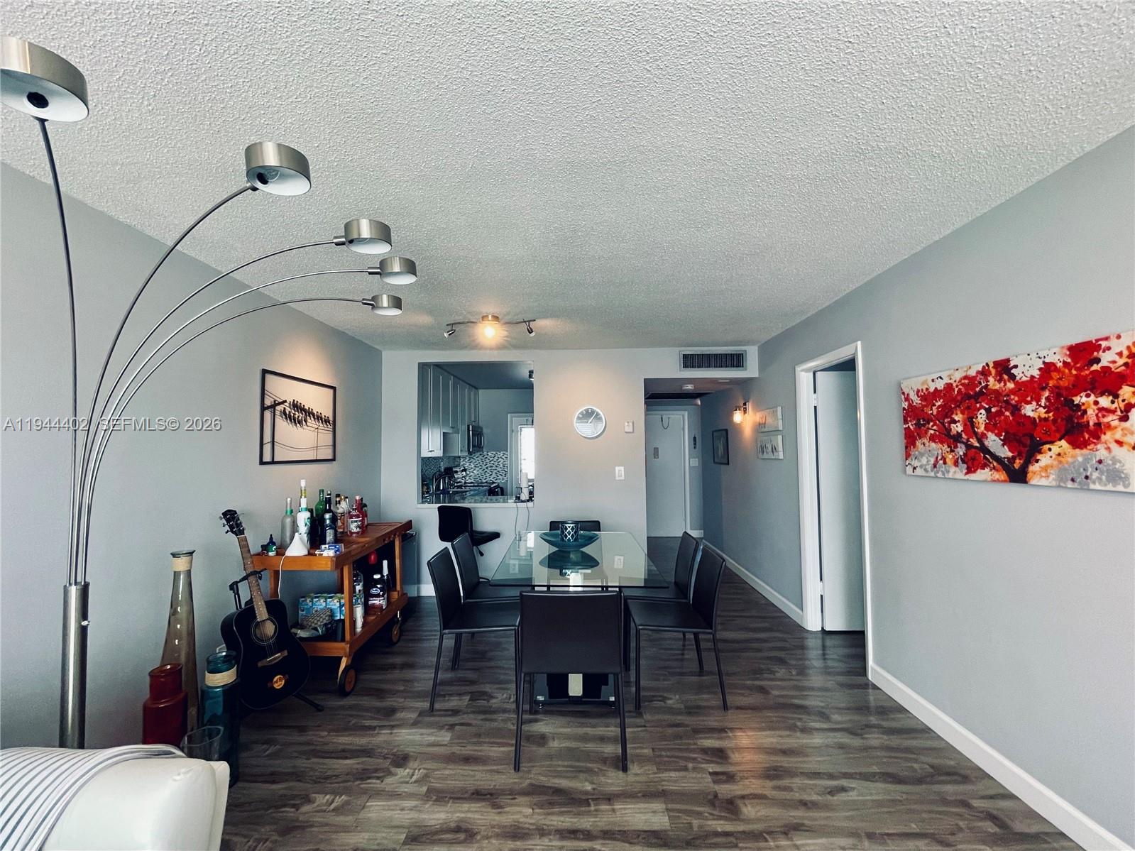 A dining area features a glass table, black chairs, a bar cart, and wood-look flooring — 2300 Park Ln # 201, Hollywood FL 33021, HOLLYWOOD, FL