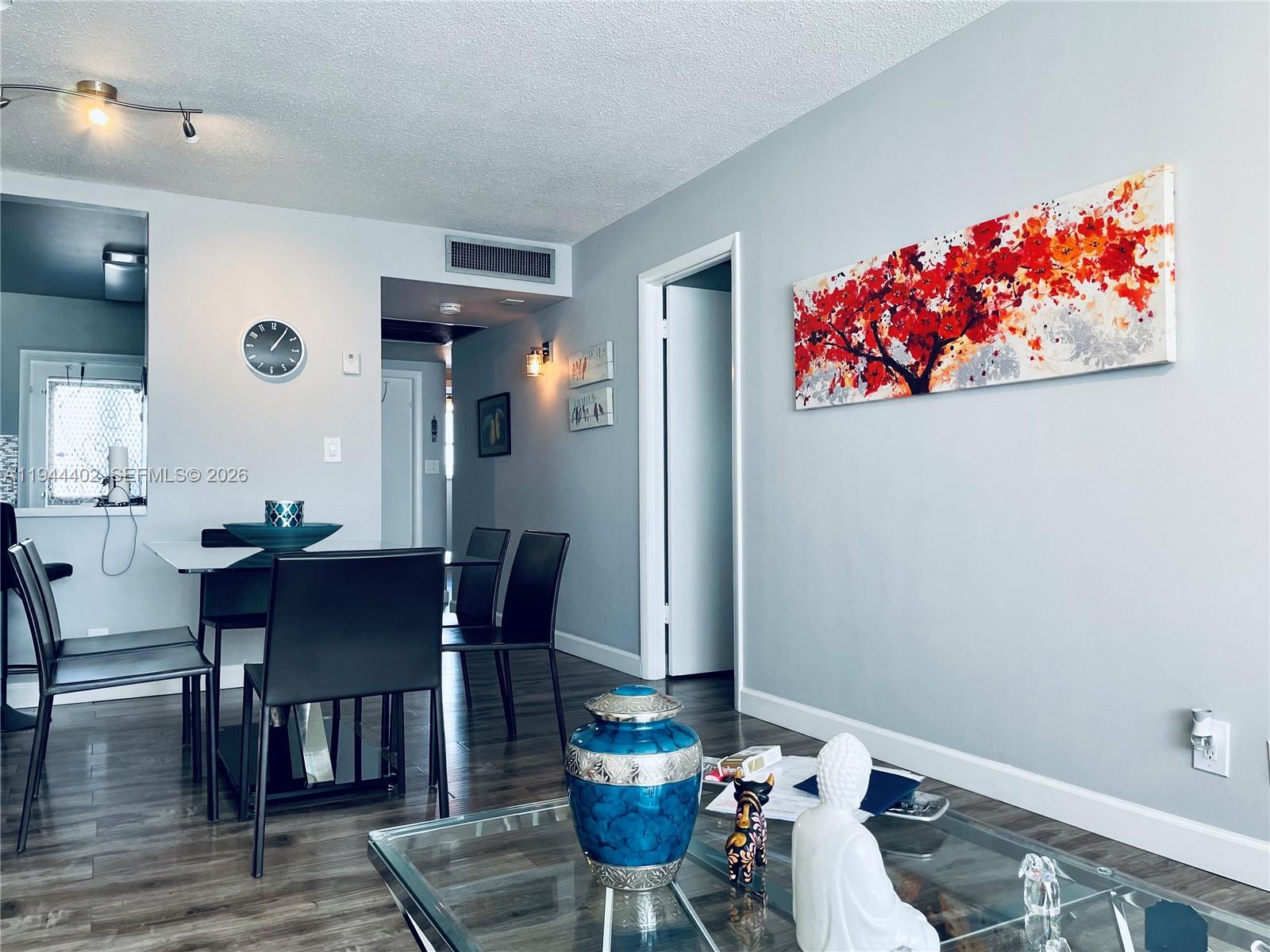 A dining area and living space feature light gray walls, dark wood floors, and modern decor — 2300 Park Ln # 201, Hollywood FL 33021, HOLLYWOOD, FL