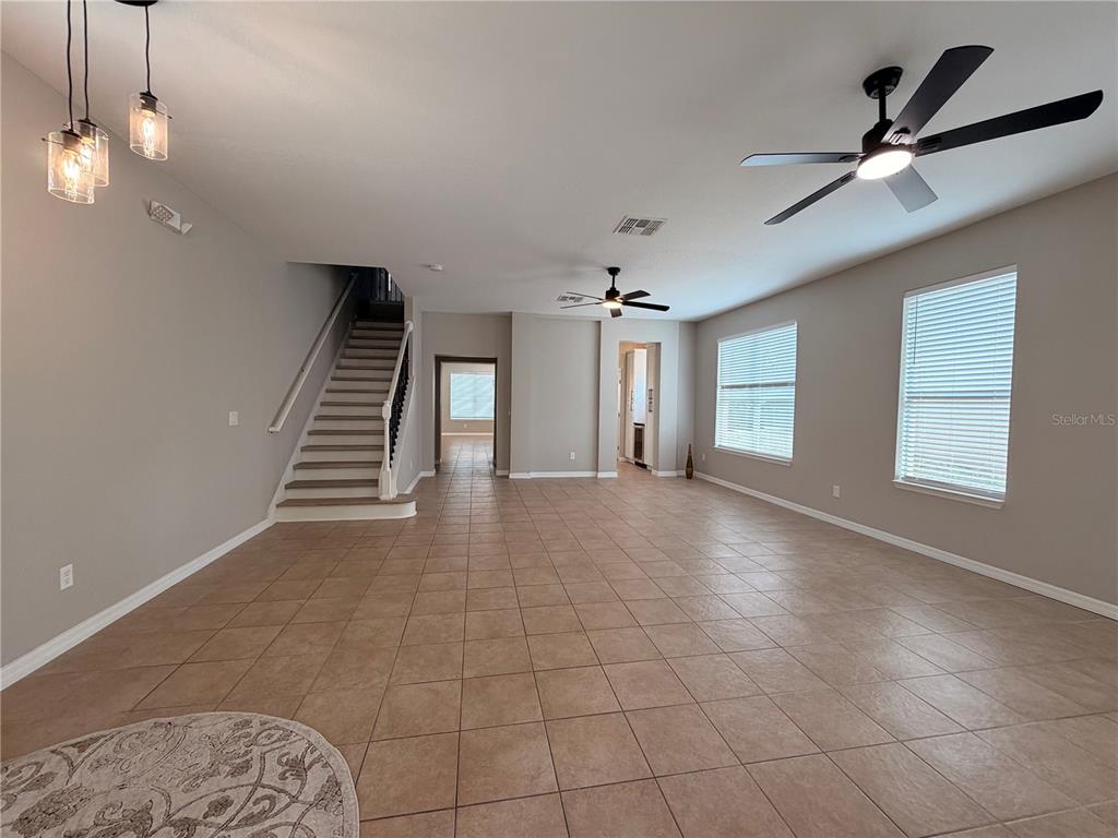 A spacious living area features tile flooring, two ceiling fans, and a staircase — 528 ORANGE COSMOS BOULEVARD, DAVENPORT, FL