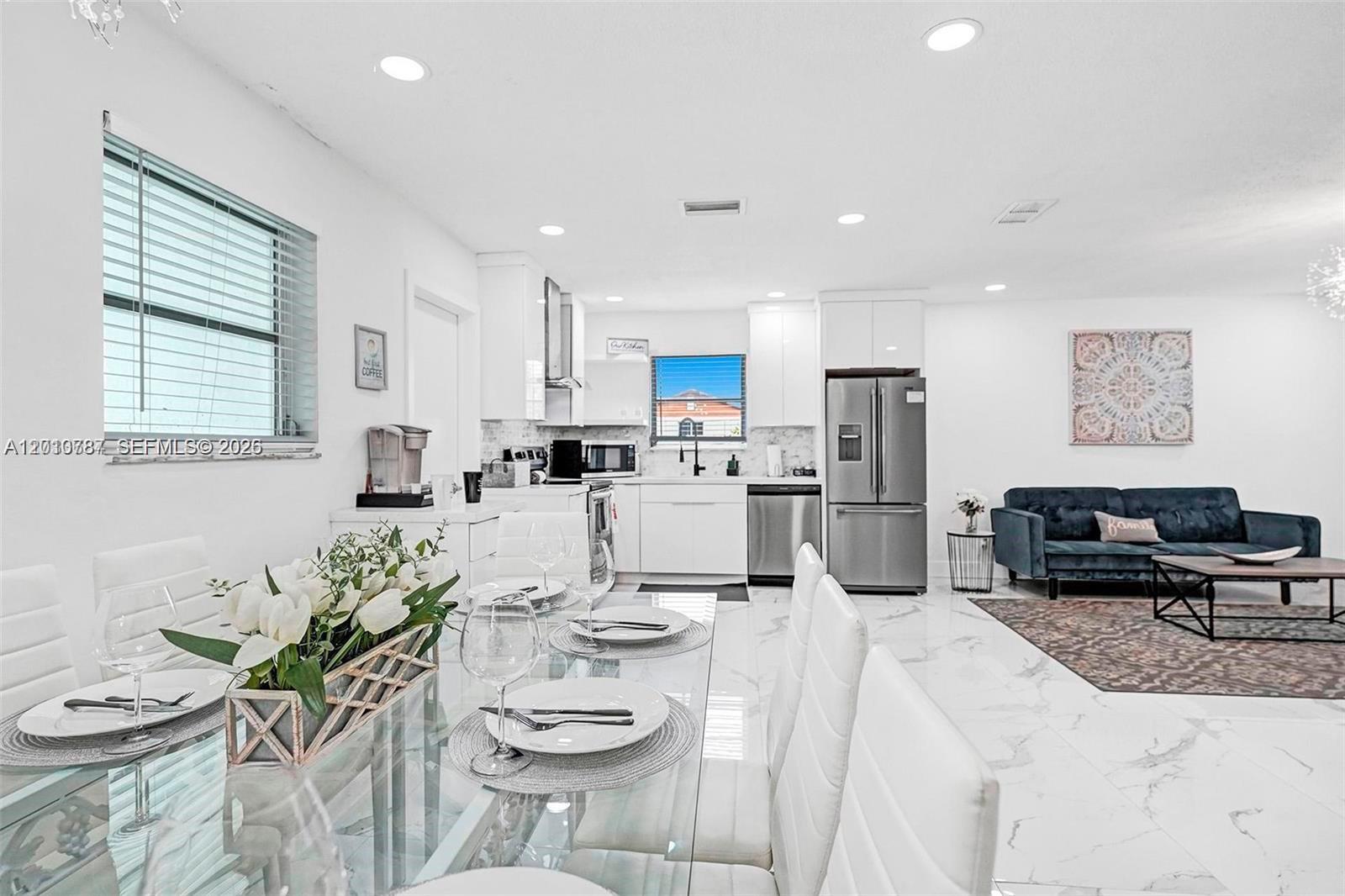 A white kitchen with stainless steel appliances opens to a dining area and living room — 2338 Fillmore St # 2A, Hollywood FL 33020, HOLLYWOOD, FL
