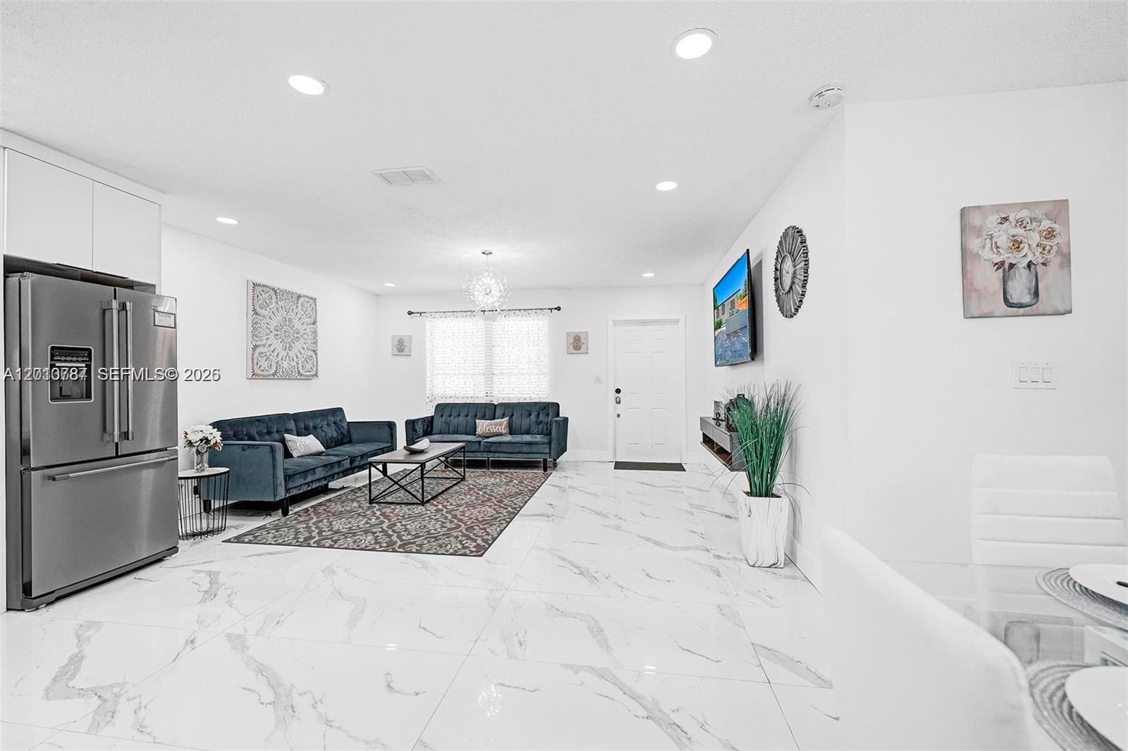 A bright open-concept living area features white marble floors, blue velvet sofas, and recessed lighting — 2338 Fillmore St # 2A, Hollywood FL 33020, HOLLYWOOD, FL