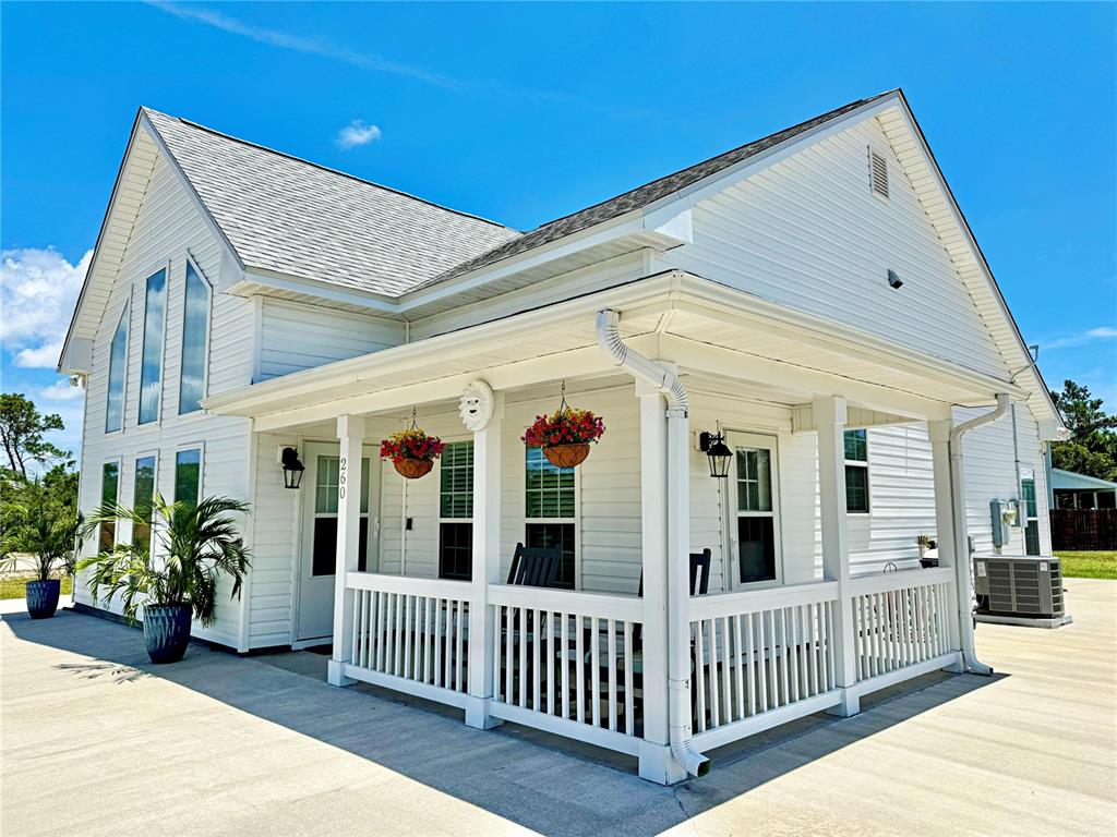 A white house with a covered porch, hanging flower baskets, and a concrete driveway — 260 BLUE HERON DRIVE, EASTPOINT, FL
