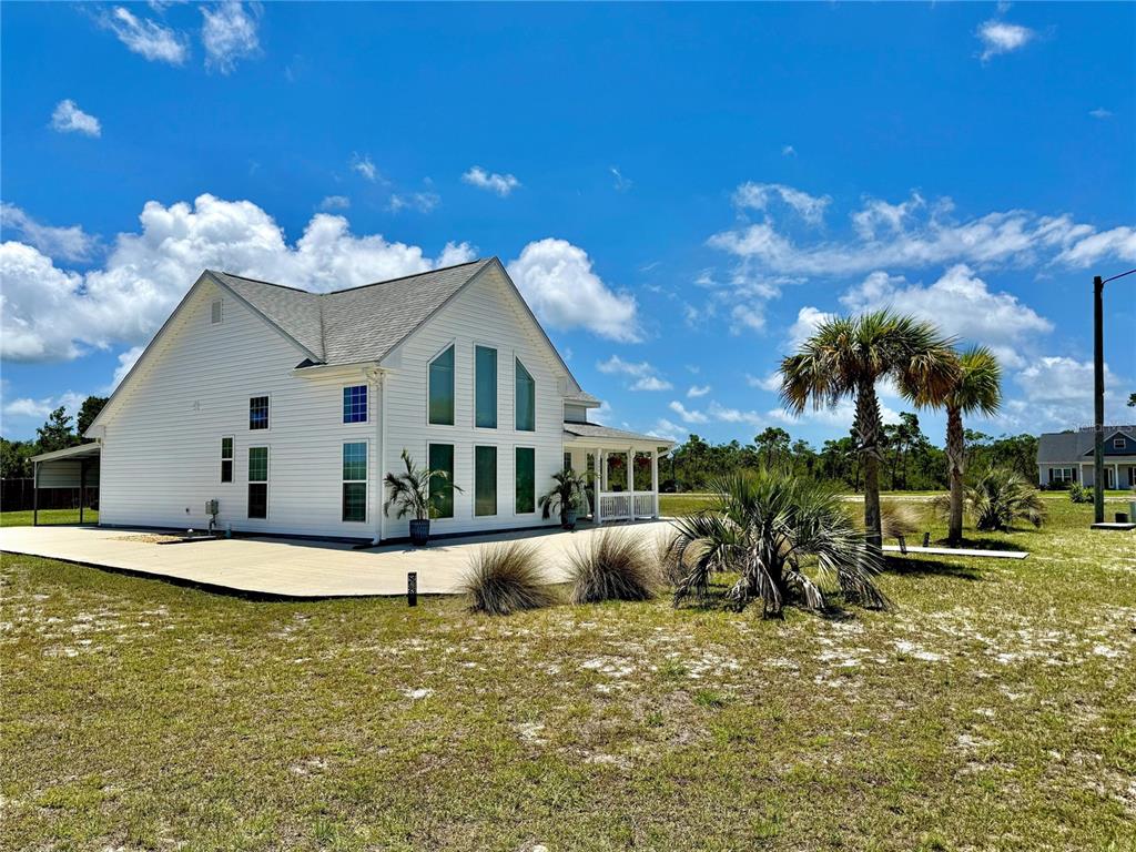 A white two-story house with a large concrete patio and palm trees in the yard — 260 BLUE HERON DRIVE, EASTPOINT, FL