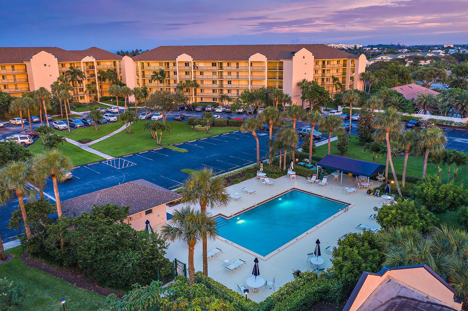 An aerial view of a multi-story apartment complex with a swimming pool and parking lot — 275 Palm Avenue # C402, Jupiter FL 33477, JUPITER, FL