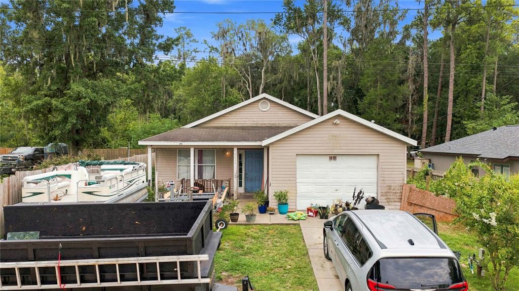 A single-story house with beige siding, a front-facing garage, and a pontoon boat parked outside — 2460 SE 69TH LANE, OCALA, FL