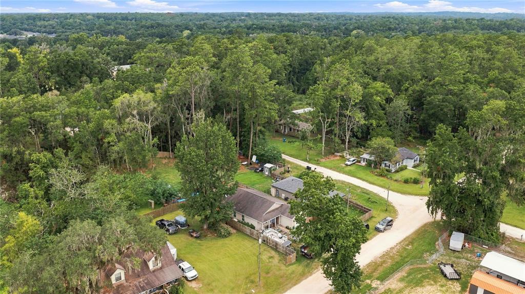 An aerial view shows several houses surrounded by dense trees and a dirt road — 2460 SE 69TH LANE, OCALA, FL